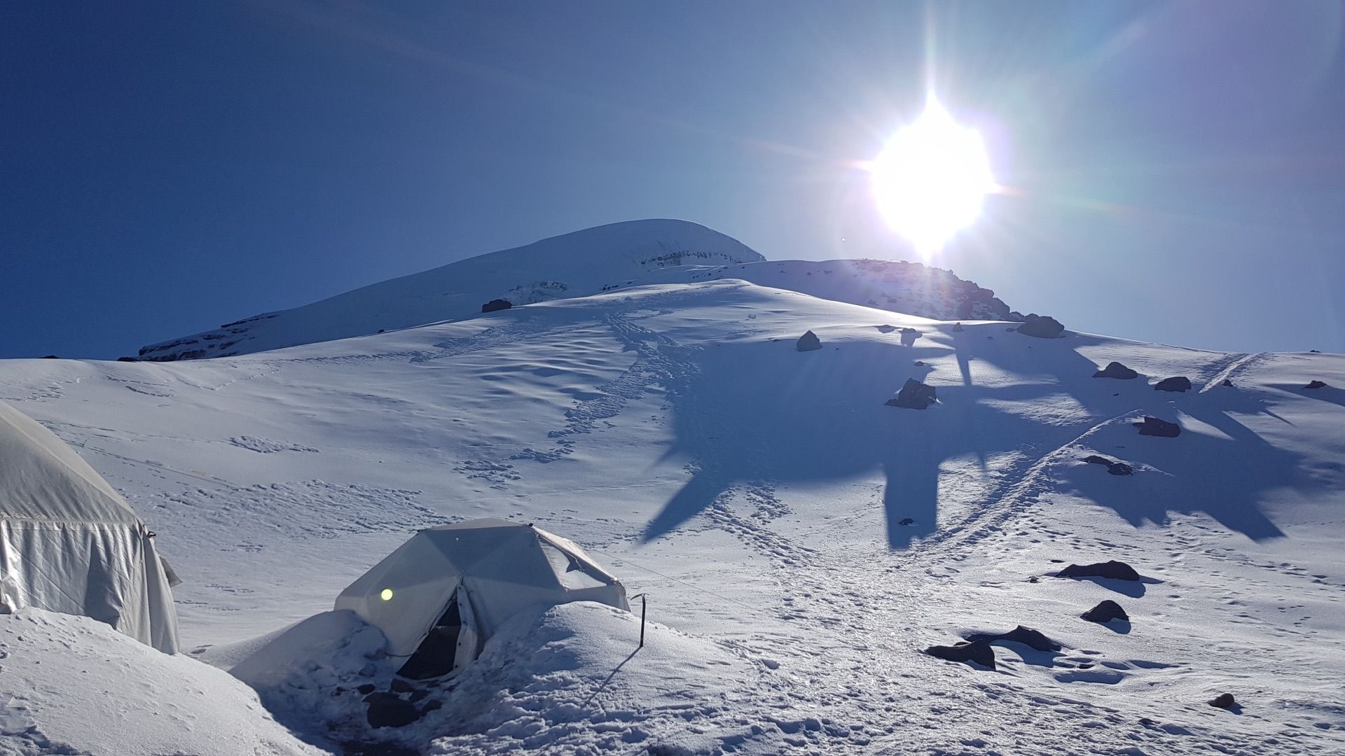 Expedition tents at Chimborazo high camp, with the summit snowfield glowing under the sun